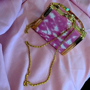 A cute little purse/ hand bag. Pink with white patterns with a gold trimming.